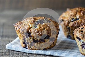 Delicious muffins with blueberries on a wooden table, closeup. Sweet pastries on the board. Fresh cupcakes for breakfast