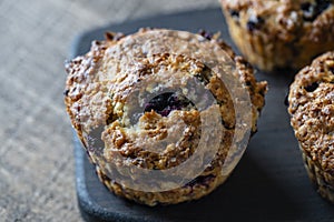 Delicious muffins with blueberries on a wooden table, closeup. Sweet pastries on the board. Fresh cupcakes for breakfast