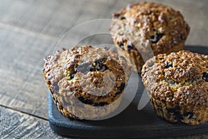 Delicious muffins with blueberries on a wooden table, closeup. Sweet pastries on the board. Fresh cupcakes for breakfast
