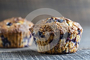 Delicious muffins with blueberries on a wooden table, closeup. Sweet pastries on the board. Fresh cupcakes for breakfast