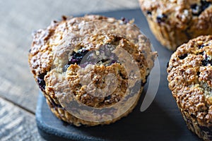 Delicious muffins with blueberries on a wooden table, closeup. Sweet pastries on the board. Fresh cupcakes for breakfast