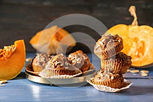 Delicious muffins with sunflower seeds and cut pumpkin on color table