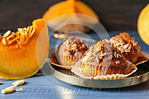 Delicious muffins with sunflower seeds and cut pumpkin on color table