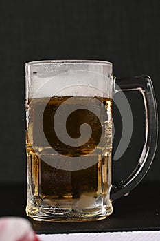 delicious mug of super cold and refreshing draft beer on the table in the blurred background