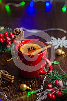 Delicious mulled wine alcoholic warm drink with cinnamon and star anise in a red cup, bokeh on the background. The concept of