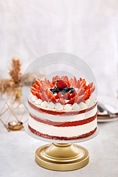 Delicious naked red velvet cake decorated with cream and fresh berries