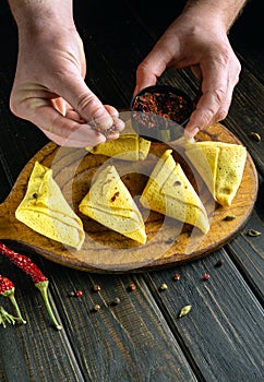 Delicious nalistniki on the kitchen board. The cook adds spices with his hands to add flavor and aroma to the rolled pancakes