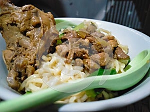 The delicious of noodle and chicken slice are displaying on the white bowl