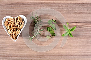 Delicious and nutritious peanuts, peeled in a heart-shaped bowl with overhead view isolated on wooden table