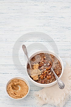 Delicious oatmeal in a white bowl, dates fruits, cocoa and vegan milk