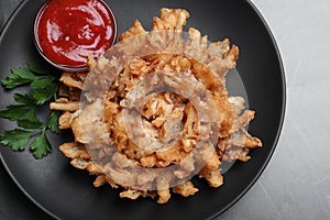 Delicious onion blossom with ketchup served on black table, top view