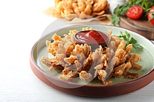 Delicious onion blossom with ketchup served on white wooden table