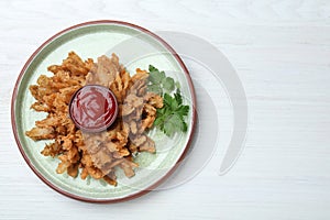 Delicious onion blossom with ketchup served on white wooden table, top view. Space for text