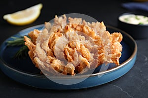 Delicious onion blossom served on black table, closeup