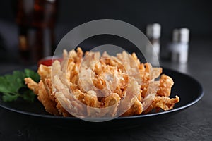 Delicious onion blossom served on black table, closeup