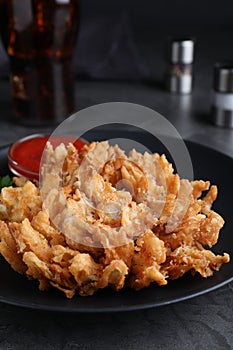 Delicious onion blossom served on black table, closeup