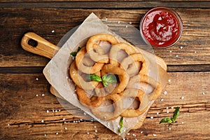 Delicious onion rings and ketchup on table, flat lay