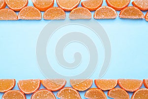 Delicious orange marmalade candies on light blue background, flat lay. Space for text