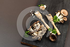 Delicious organic oyster mushrooms with spices and fresh parsley on wooden cutting board