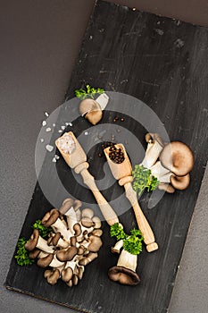 Delicious organic oyster mushrooms with spices and fresh parsley on wooden cutting board