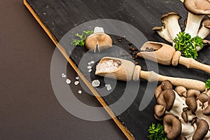 Delicious organic oyster mushrooms with spices and fresh parsley on wooden cutting board