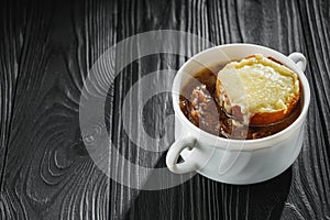 delicious original french onion soup on a black rustic wooden background