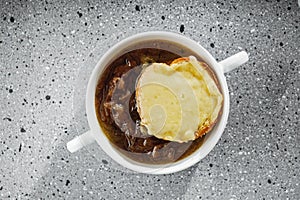 delicious original French onion soup on a light stone background