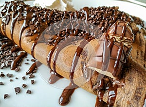 Delicious pancake crepe filled with chocolate and chocolate topping, crumbs, bar and whipped cream served as tasty dessert cheat