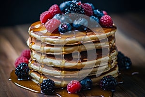 Delicious pancakes with maple syrup and fresh berries served on rustic wooden background