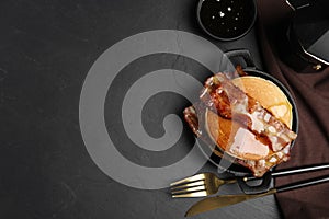 Delicious pancakes with maple syrup and fried bacon on black table, flat lay. Space for text