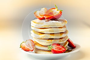 Delicious pancakes stacked with fresh sweet strawberries, topped with maple syrup