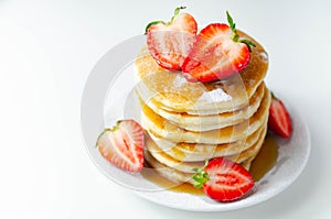 Delicious pancakes stacked with fresh sweet strawberries, topped with maple syrup