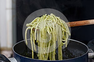 Delicious pasta with basil pesto sauce on fork, closeup