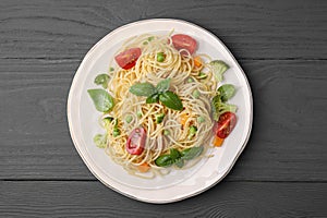 Delicious pasta primavera with tomatoes, basil and broccoli on grey table, top view