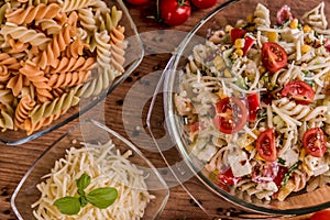 Delicious pasta salad or Mediterranean salad. Tomatoes with mozzarella basil corn spice and olive oil on a wooden table.