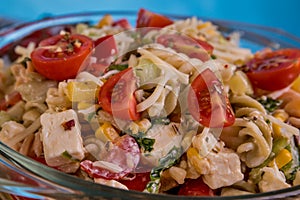 Delicious pasta salad or Mediterranean salad. Tomatoes with mozzarella basil corn spice and olive oil on a wooden table.