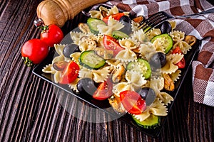 Delicious pasta salad with tomato cucumber and olives on wooden rustic background