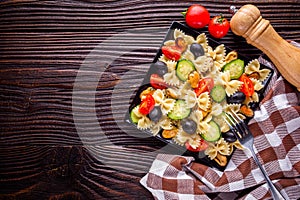 Delicious pasta salad with tomato cucumber and olives on wooden rustic background