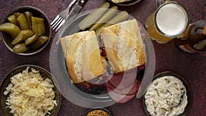 Delicious pastrami meat sandwiches served with glass of beer, pickles, potato chips and sides.