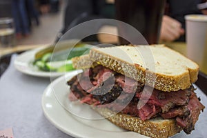 Delicious pastrami sandwich with side of pickles