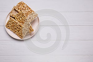 Delicious peanut bars (kozinaki) on white wooden table, top view. Space for text