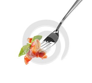 Delicious penne pasta with tomato sauce on fork against background