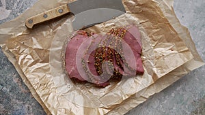 Delicious peppered roast beef pastrami slices on paper with grains of coloured pepper