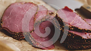 Delicious peppered roast beef pastrami slices on paper with grains of coloured pepper