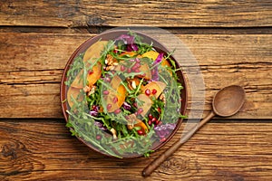 Delicious persimmon salad served on wooden table, flat lay