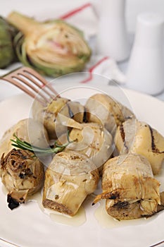 Delicious pickled artichokes with rosemary on plate, closeup