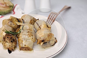 Delicious pickled artichokes with rosemary served on white table, closeup