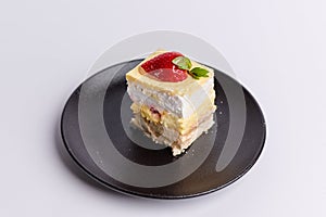 Delicious piece of white Shortcake on a black plate, decorated with fresh red strawberries