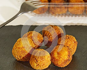 Delicious Pincho of several round croquettes making an horizontal circle on a black slate board decorated with croquettes in a