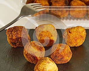 Delicious Pincho of several round croquettes making an horizontal pyramid on a black slate board decorated with croquettes in a